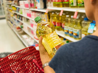 woman looking at vegetable oil bottle in grocery store