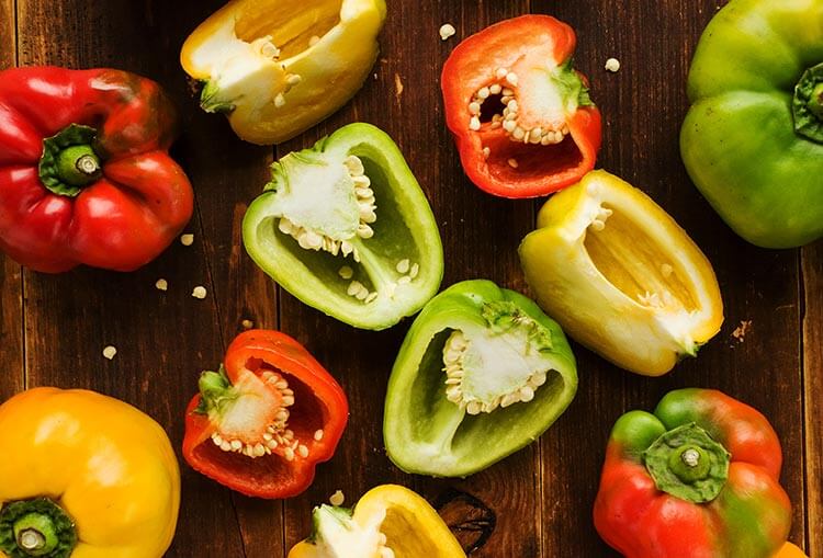 colorful bell peppers on wooden background