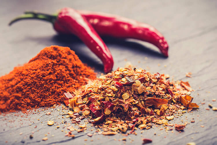 closeup of chili peppers, powder, and seeds 