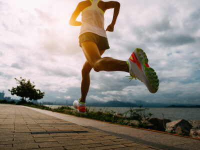 Fitness woman running training for marathon on sunny coast trail