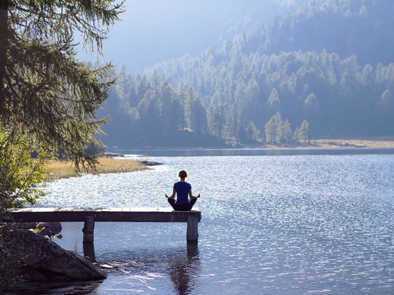 person practicing modern yoga on ramp overlooking a lake and mountains