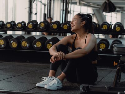 woman resting near weights in gym, post-workout recovery