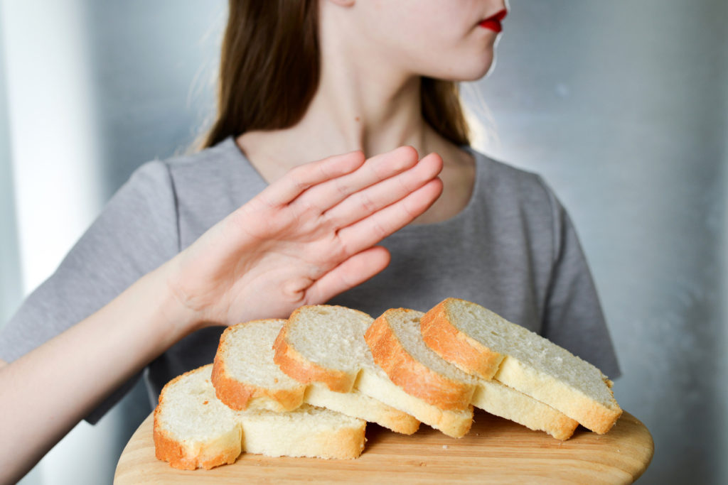 Gluten intolerance concept. Young woman refuses to eat white bread - shallow depth of field