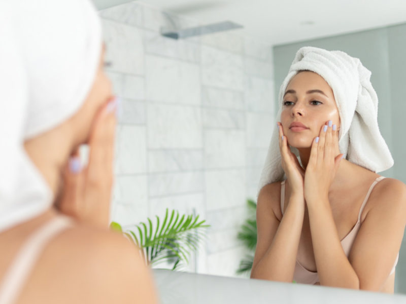 woman applying skincare product in front of mirror