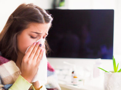 photo of young, sick woman blowing nose