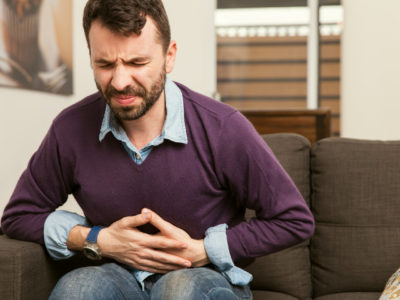 photo of man feeling unwell, holding stomach in pain