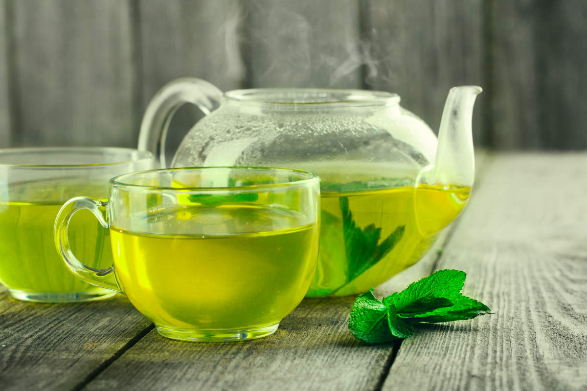 Mug of green tea and teapot on wood table | Caffeine Alternatives For A Natural Energy Boost