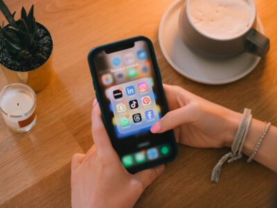 Woman uses a smartphone at a table with candle, plant, and latte