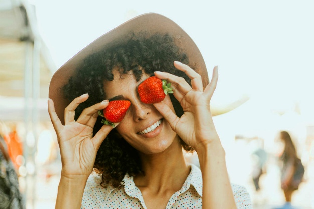 Woman holding two strawberries | What Is Ellagic Acid? Foods That Contain Ellagic Acid