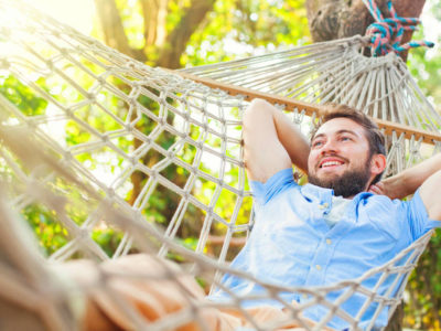 photo of smiling man swinging in hammock