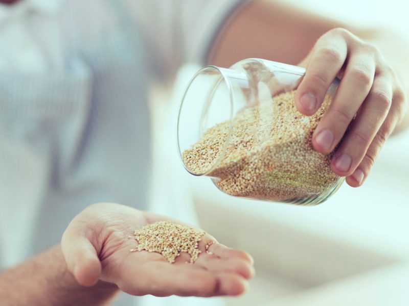 Man pouring a jar of quinoa into hand