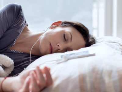 photo of woman sleeping listening to sleep music through headphones