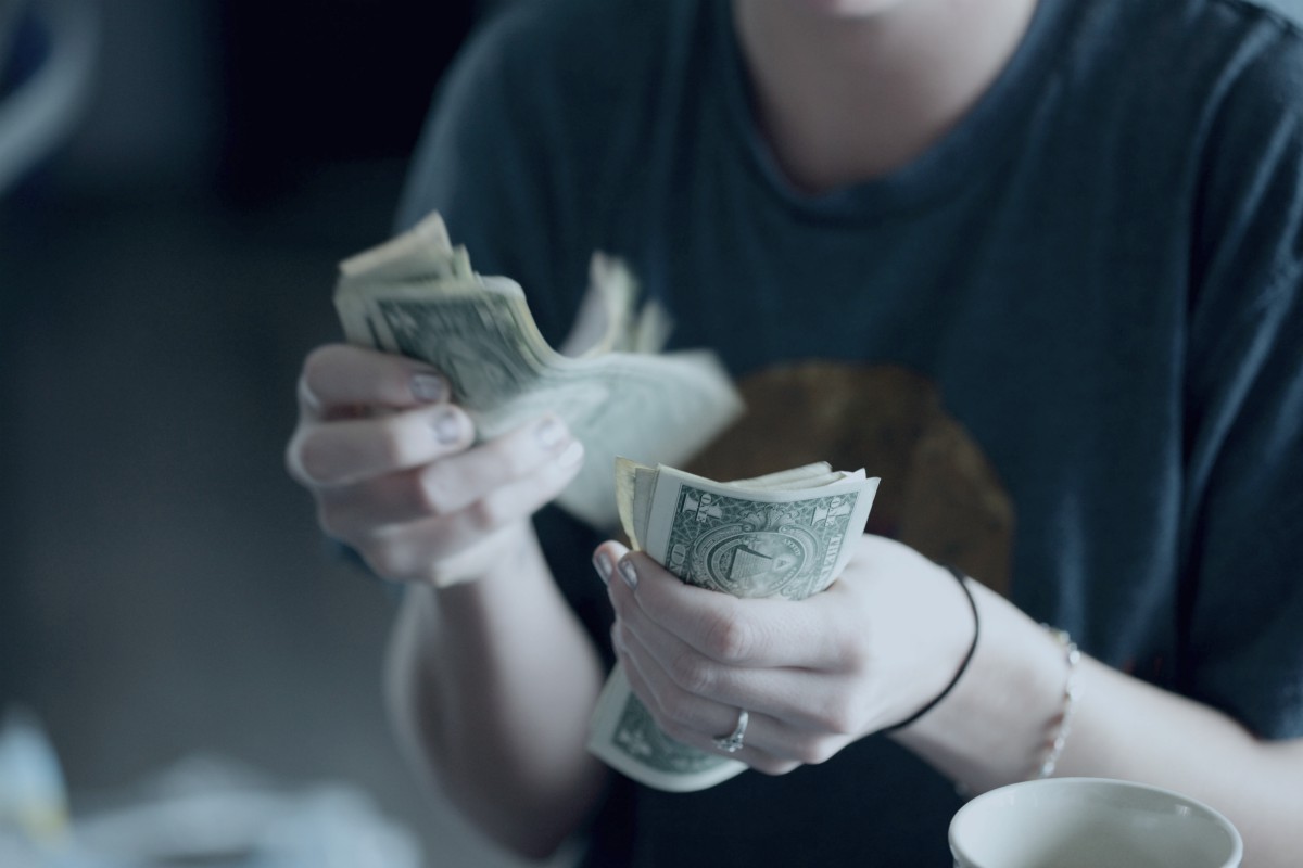 woman counting money closeup at hands | grow financial | sustainable investing | sustainable source of income