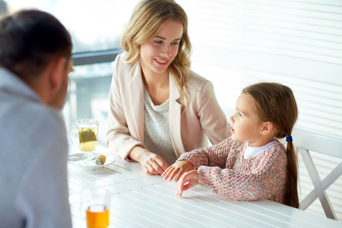 little girl talking to mom and dad at a table | parenthood family communication | good habits | good eating habits | good sleep habits