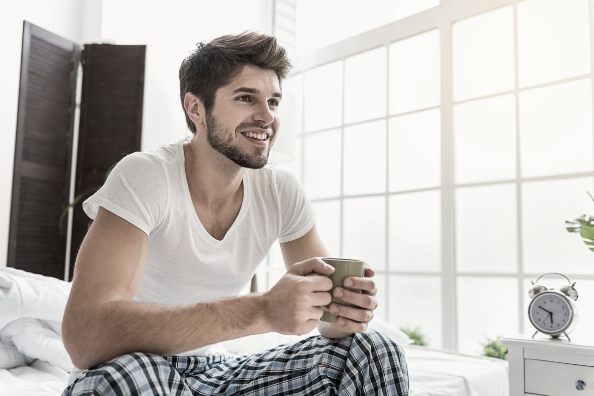 man sitting on the bed drinking a cup of coffee early morning | good habits | good sleeping habits | good daily habits