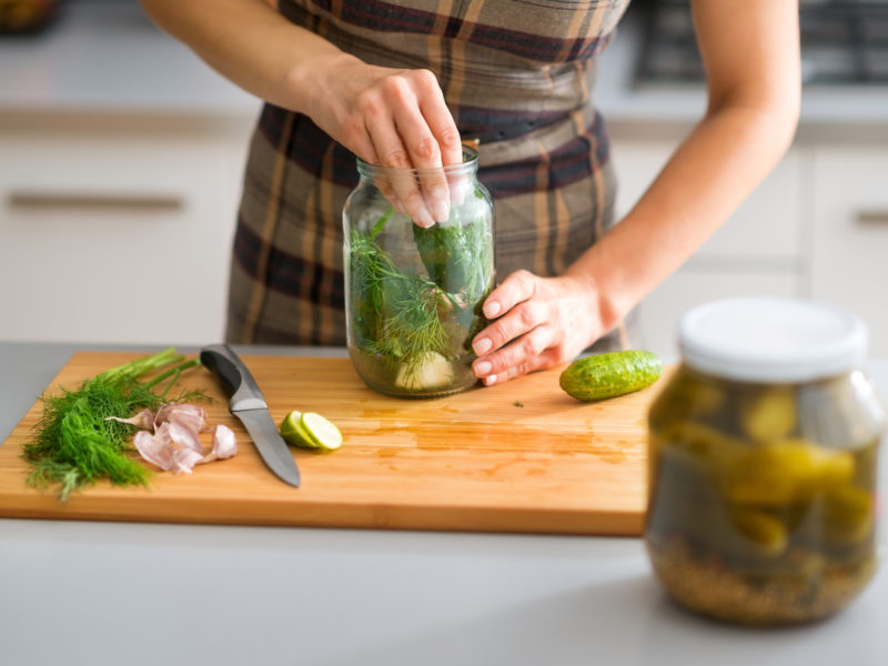 photo of woman filling jars with pickles