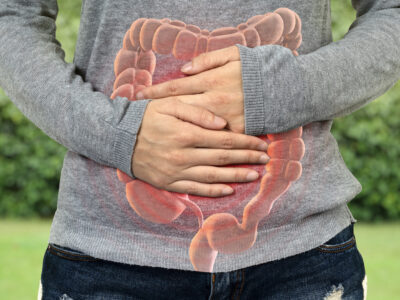 colon image overlaid on person; person holding stomach in pain