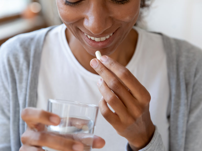 photo of woman taking a probiotic pill with water