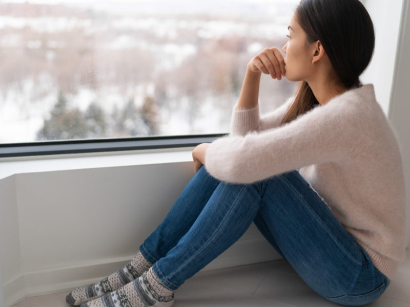 sad woman looking out of window during winter