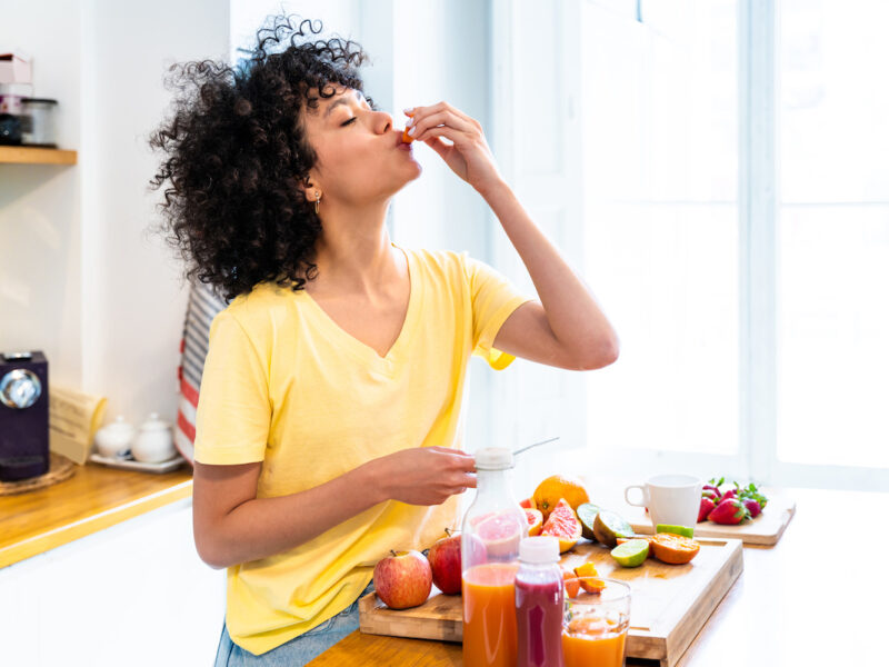 photo of a young woman preparing and enjoying healthy food at kitchen counter