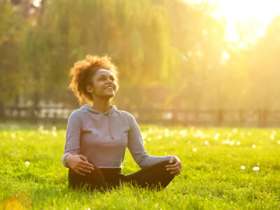 photo of calm healthy woman sitting in grass in sun