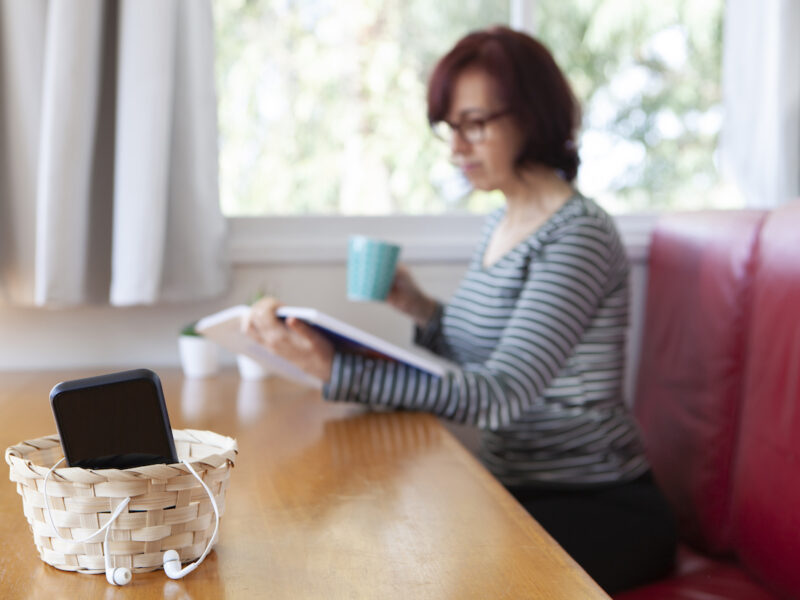 photo of a woman doing a digital detox with phone in a basket when she reads and sips coffee