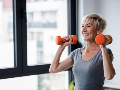 Senior woman doing strengthening exercises, lifting dumbbells