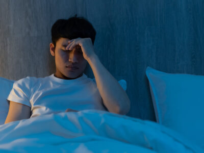 close up of asian young man with insomnia worrying about something in bed at night