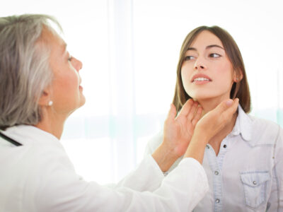 female doctor feeling patients thyroid