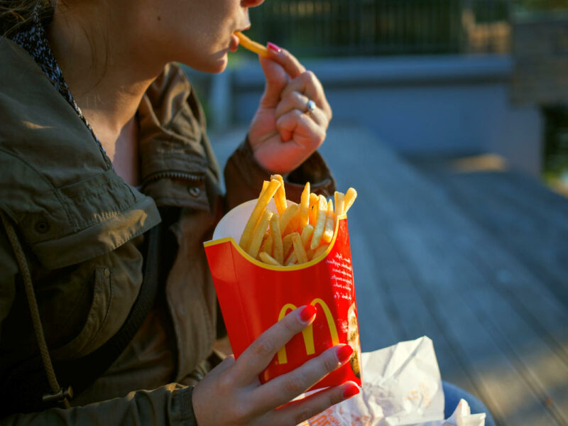 woman eating McDonald's french fries outdoors