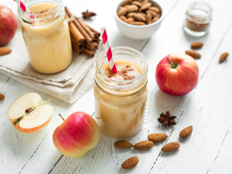 Apple pie protein smoothie drink with almond milk. Homemade apple smoothie with apple pie spices (cinnamon) on white wooden background.