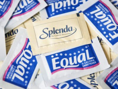 photo of artificial sweeteners; Splenda and Equal Product Shot zero calorie sweeteners: Splenda in a yellow packet, Equal in a blue packet.