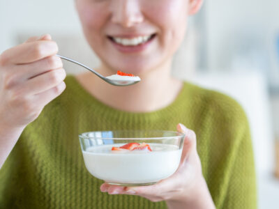 photo of smiling woman eating yogurt for gut health