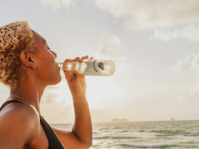 woman at a beach drinking a bottle of mineral water