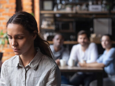 Upset woman suffering from bullying, excluded girl having problem with bad friends, feeling offended and hurt, sitting alone in cafe, avoiding people