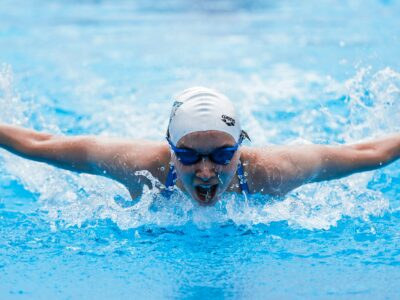 person in swimming goggles and cap swimming in pool